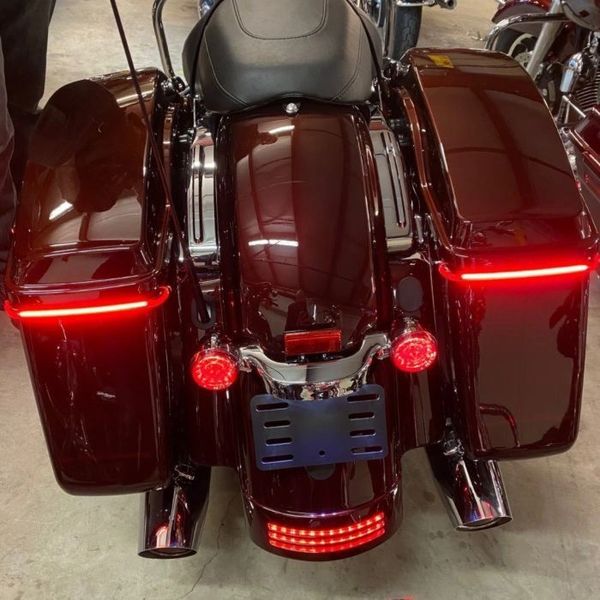 A red motorcycle parked in a garage with its lights on.