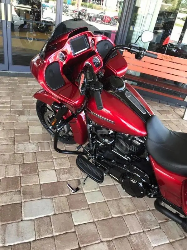 A red motorcycle parked on the side of a brick road.