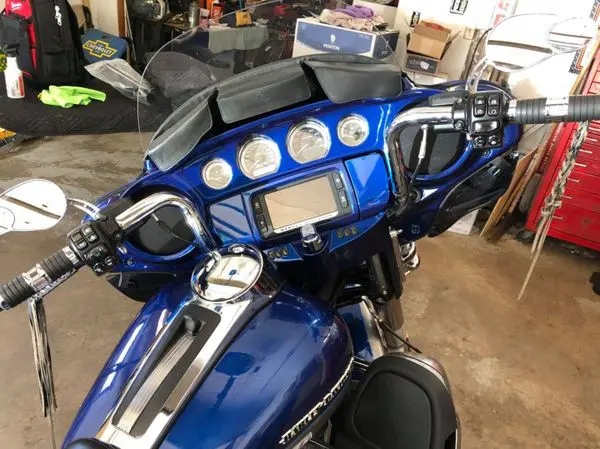 A blue motorcycle parked in a garage with its dashboard.