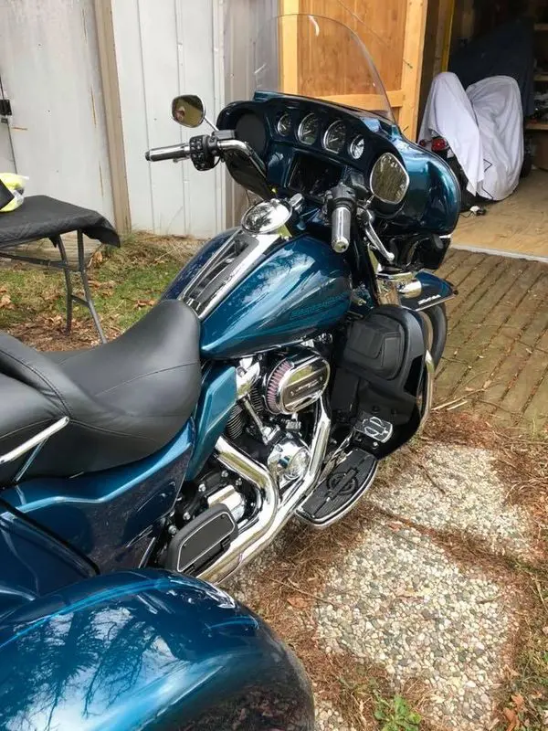 A blue motorcycle parked in the driveway of a house.