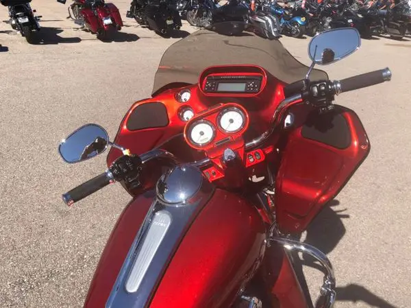 A red motorcycle parked in the street with other motorcycles.