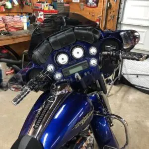 A motorcycle is parked in the garage with its helmet on.