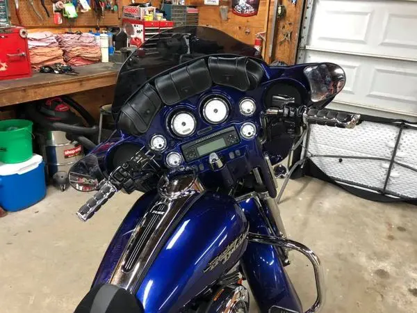 A motorcycle is parked in the garage with its helmet on.