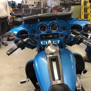 A blue motorcycle parked in the garage with other motorcycles.