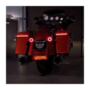 A red motorcycle parked in the dark with its lights on.