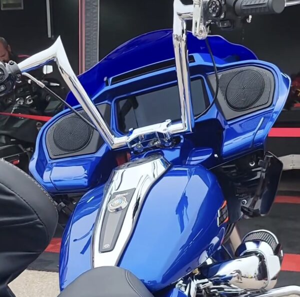 Blue motorcycle with chrome handlebars and speakers.